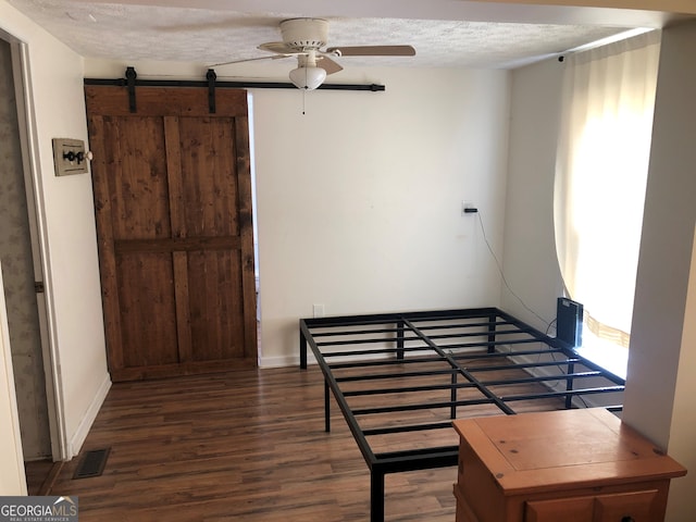 bedroom with multiple windows, dark hardwood / wood-style floors, and a textured ceiling