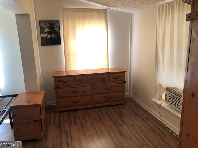 bedroom featuring dark hardwood / wood-style flooring, cooling unit, and a textured ceiling