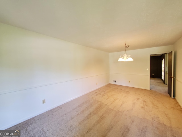 spare room with carpet and a chandelier