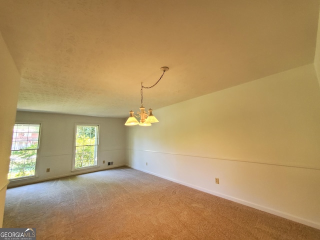 empty room featuring carpet floors and an inviting chandelier