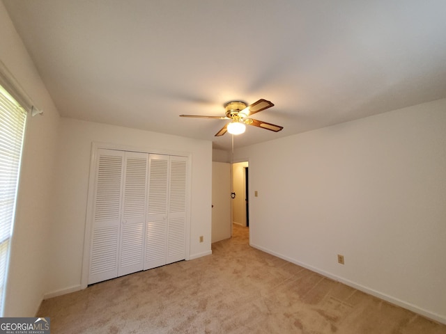 unfurnished bedroom featuring ceiling fan, light colored carpet, and a closet