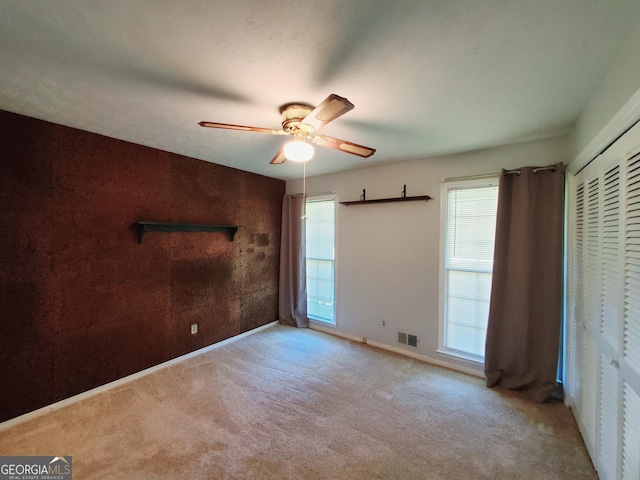 unfurnished bedroom featuring ceiling fan, light carpet, and a closet