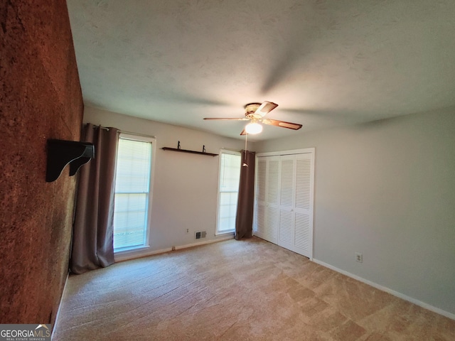 unfurnished bedroom featuring ceiling fan, light carpet, and a closet