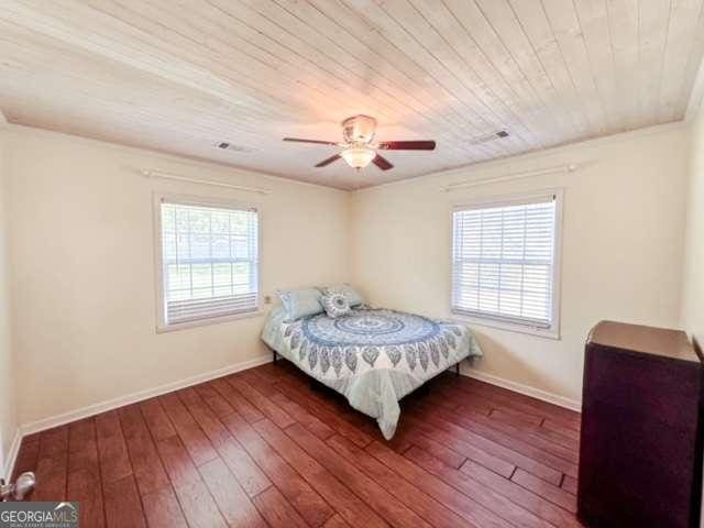 bedroom with ceiling fan, dark hardwood / wood-style flooring, and wood ceiling