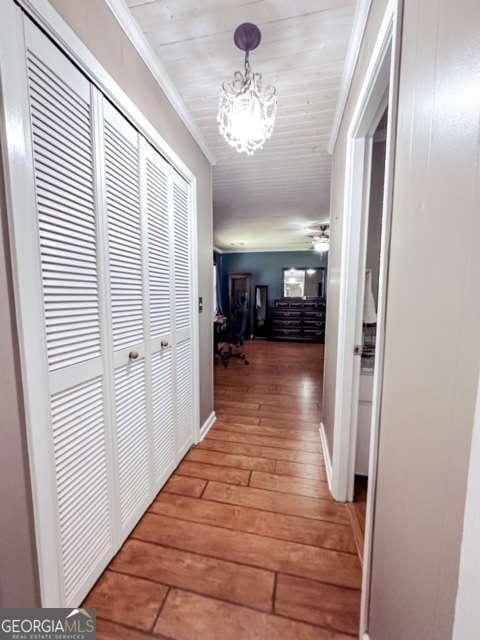 hallway featuring a chandelier, hardwood / wood-style floors, and ornamental molding