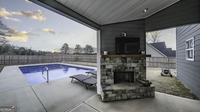 view of swimming pool featuring an outdoor stone fireplace and a patio