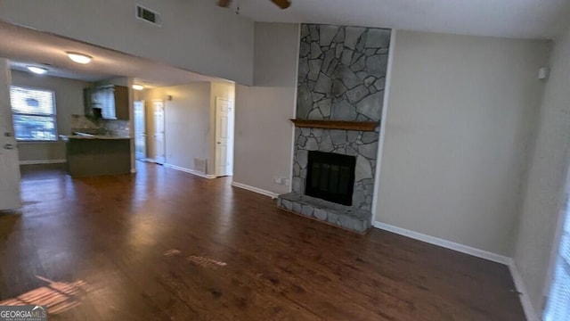 unfurnished living room featuring ceiling fan, a fireplace, and dark hardwood / wood-style floors