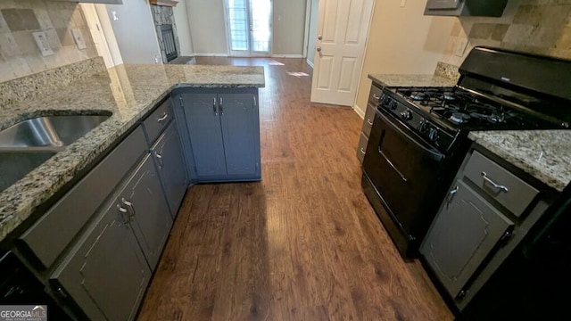 kitchen featuring a fireplace, light stone counters, black range with gas cooktop, and dark wood-type flooring