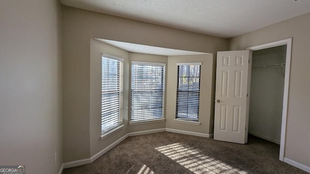 unfurnished bedroom featuring dark colored carpet, a textured ceiling, and a closet