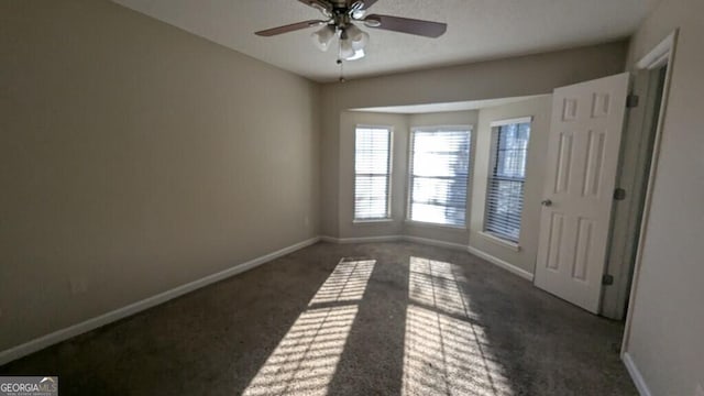 spare room featuring ceiling fan and dark colored carpet