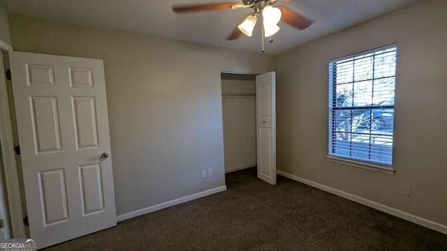 unfurnished bedroom with dark colored carpet, a closet, and ceiling fan