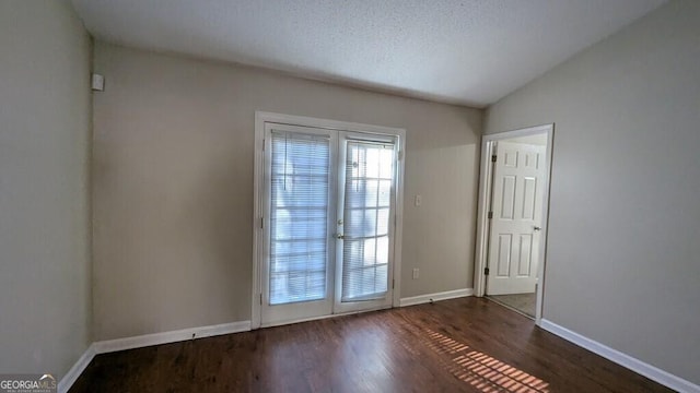 interior space with a textured ceiling, dark hardwood / wood-style flooring, and vaulted ceiling