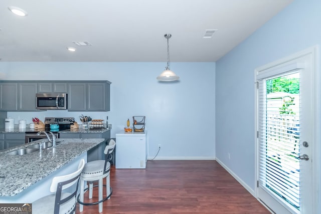 kitchen with appliances with stainless steel finishes, light stone counters, gray cabinetry, sink, and decorative light fixtures