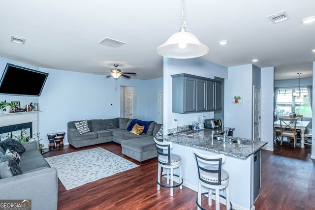 living room with a premium fireplace, ceiling fan, dark wood-type flooring, and sink