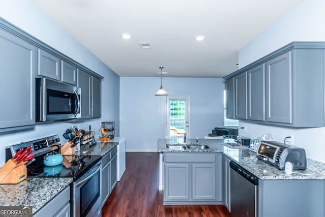 kitchen with kitchen peninsula, gray cabinetry, stainless steel appliances, and decorative light fixtures