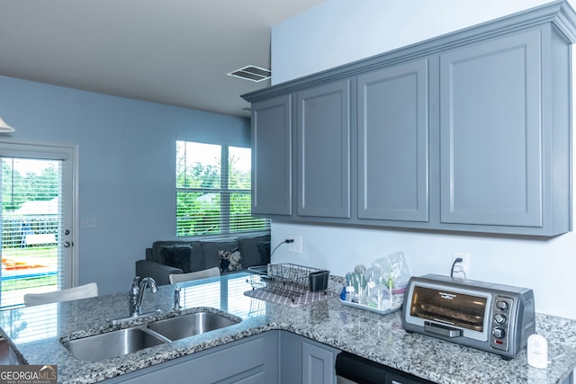 kitchen with gray cabinets, light stone countertops, and sink