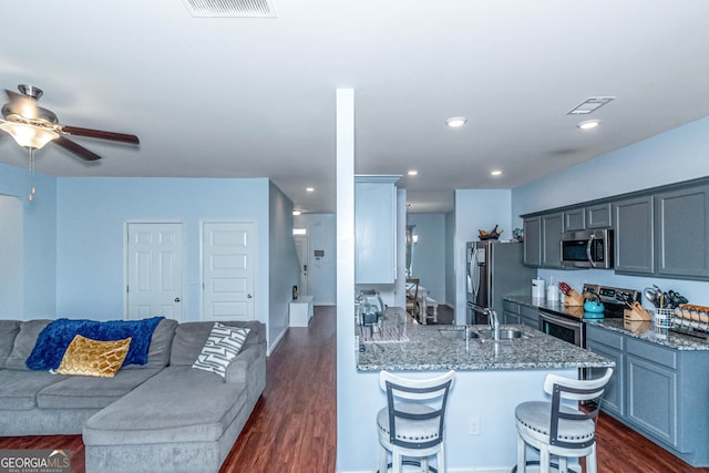 kitchen featuring sink, a kitchen breakfast bar, dark hardwood / wood-style floors, kitchen peninsula, and appliances with stainless steel finishes