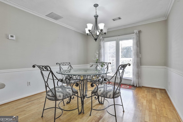 dining area with a chandelier, light wood-type flooring, and ornamental molding