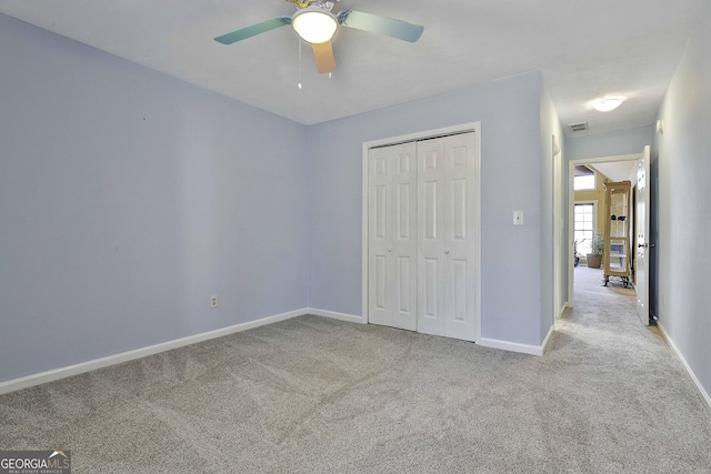 unfurnished bedroom with ceiling fan, light colored carpet, and a closet