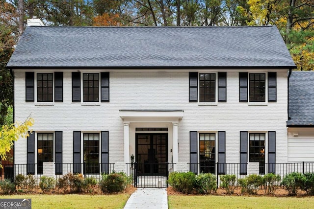 colonial-style house featuring a front lawn