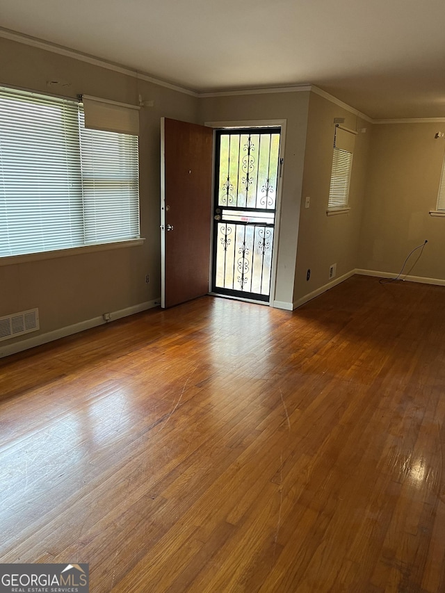 empty room with hardwood / wood-style flooring and crown molding