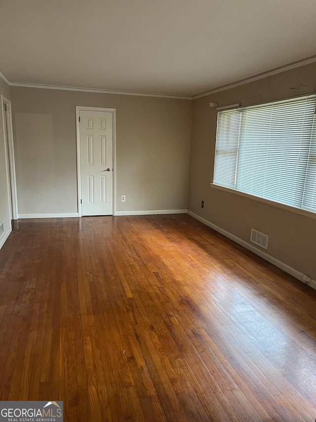 unfurnished room with hardwood / wood-style flooring and crown molding