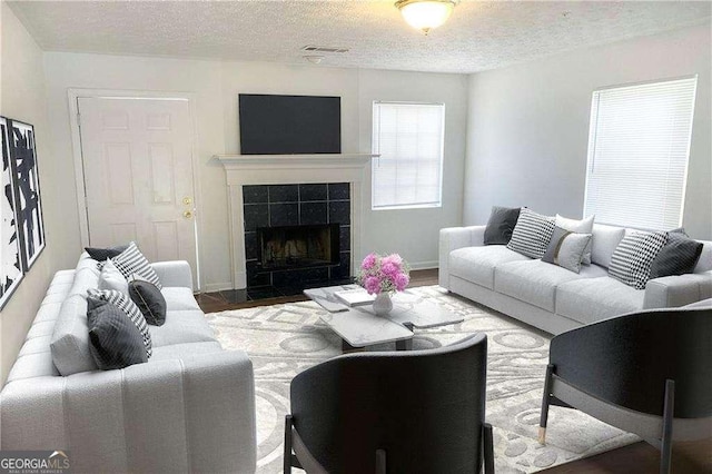 living room featuring a tiled fireplace, hardwood / wood-style floors, and a textured ceiling