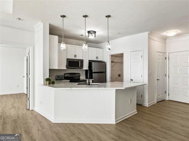 kitchen with decorative light fixtures, stainless steel appliances, white cabinetry, and light hardwood / wood-style flooring