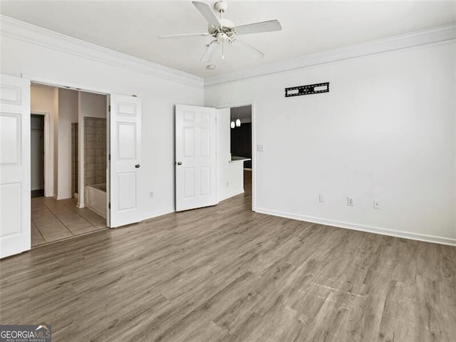 unfurnished bedroom featuring wood-type flooring, ensuite bathroom, ceiling fan, and ornamental molding