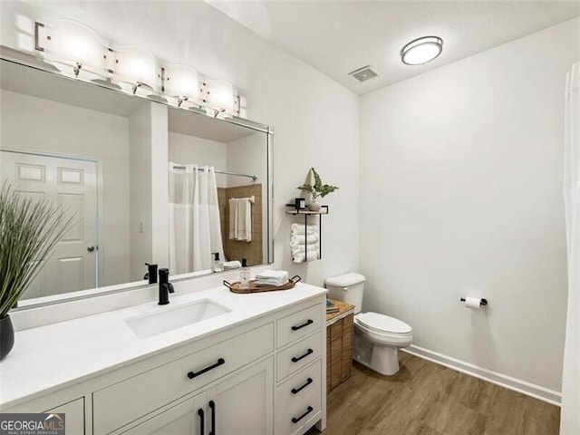 bathroom featuring wood-type flooring, vanity, toilet, and walk in shower