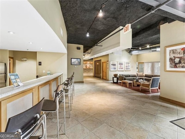 interior space featuring stainless steel refrigerator, rail lighting, and a high ceiling