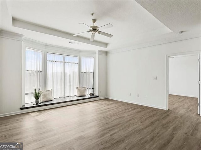 spare room with a textured ceiling, a raised ceiling, ceiling fan, and dark wood-type flooring