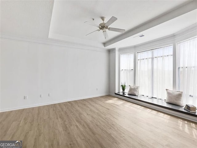 spare room with ceiling fan, a raised ceiling, and light wood-type flooring