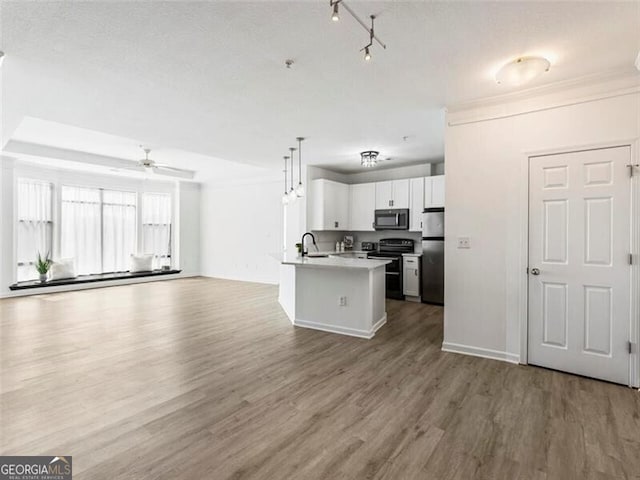 kitchen with stainless steel fridge, sink, electric range, white cabinetry, and hanging light fixtures