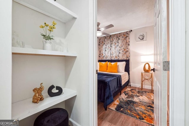 bedroom with hardwood / wood-style flooring, ceiling fan, and a textured ceiling