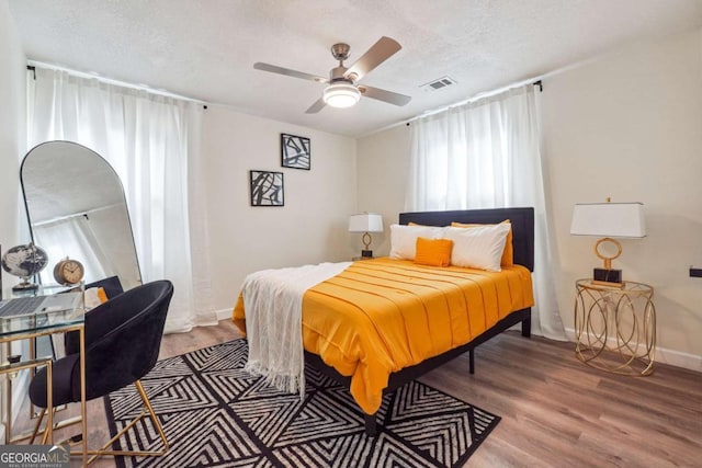 bedroom with hardwood / wood-style floors, ceiling fan, and a textured ceiling