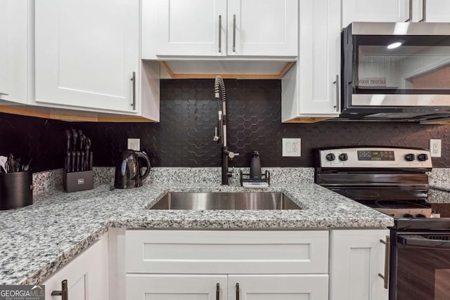 kitchen featuring sink, light stone counters, backsplash, white cabinets, and appliances with stainless steel finishes