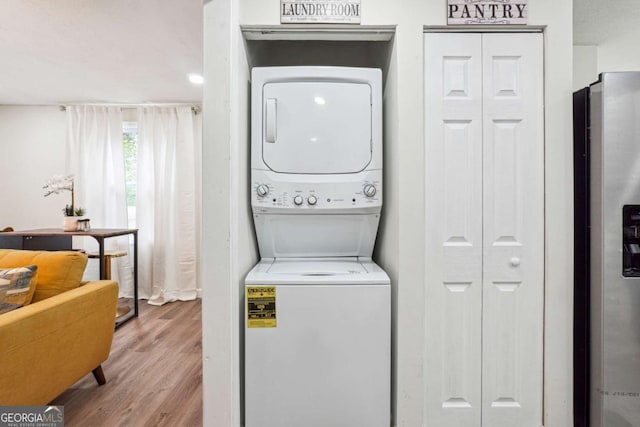 laundry room with light hardwood / wood-style flooring and stacked washer / drying machine