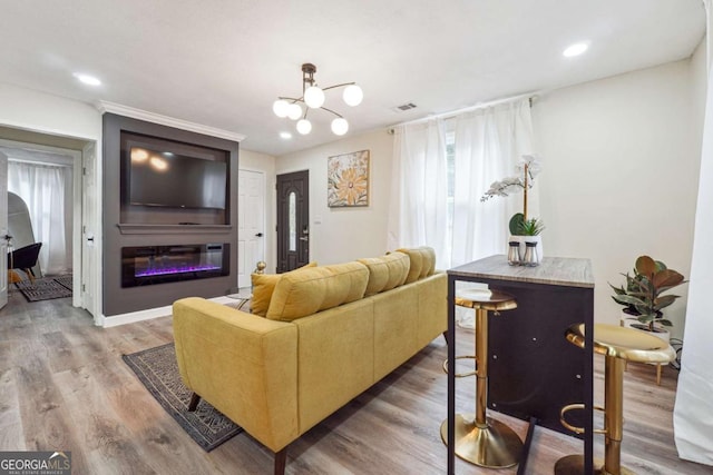 living room with wood-type flooring, a large fireplace, and a notable chandelier