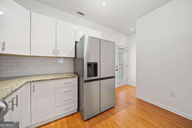 kitchen featuring white cabinets, stainless steel fridge with ice dispenser, light hardwood / wood-style flooring, and tasteful backsplash