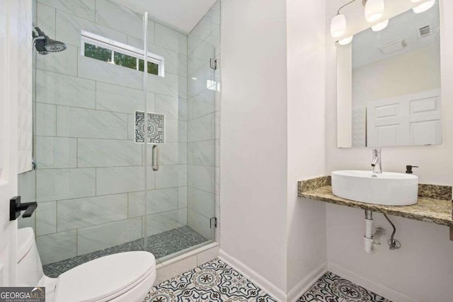 bathroom with toilet, a shower with door, tile patterned floors, and sink