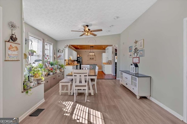 dining room featuring lofted ceiling, light wood finished floors, visible vents, and a textured ceiling