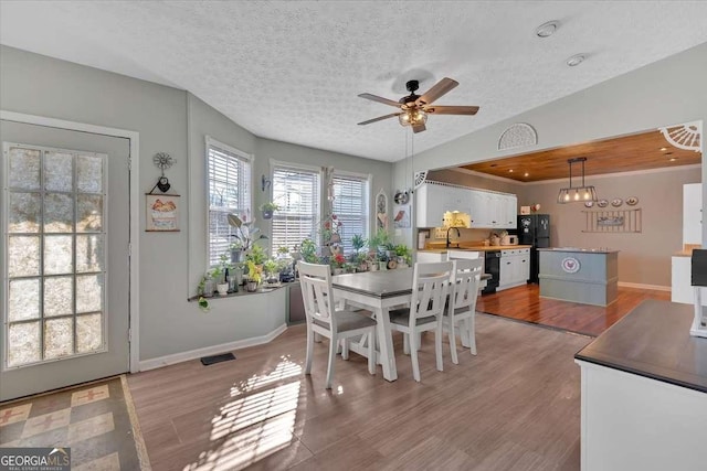 dining room with vaulted ceiling, visible vents, a textured ceiling, and light wood-style flooring