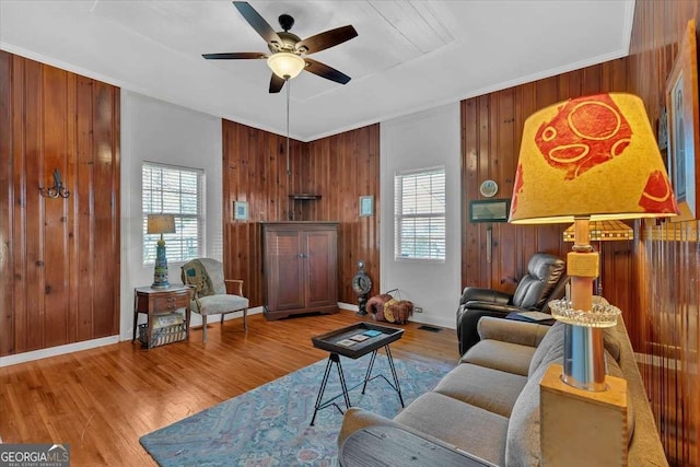 living room with a healthy amount of sunlight, wooden walls, and wood finished floors