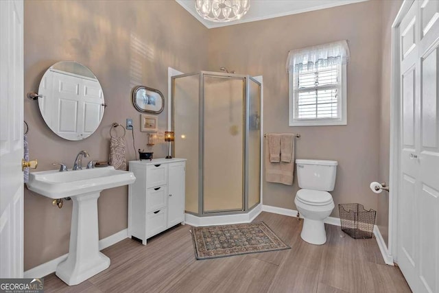 full bathroom with toilet, a stall shower, baseboards, and wood finished floors