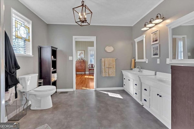 full bath with crown molding, double vanity, toilet, a sink, and baseboards