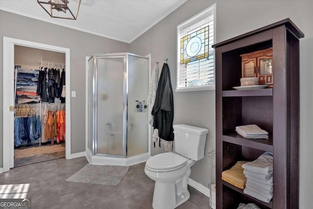 full bathroom with a walk in closet, crown molding, toilet, a stall shower, and baseboards