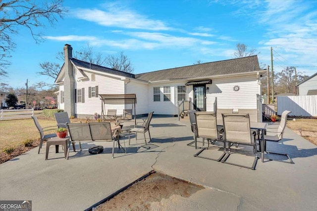 rear view of property with a patio, outdoor dining area, and fence