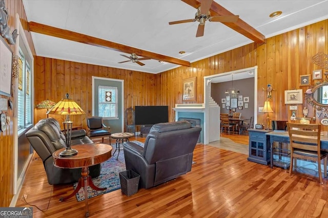 living room with ceiling fan with notable chandelier, beamed ceiling, and wood finished floors