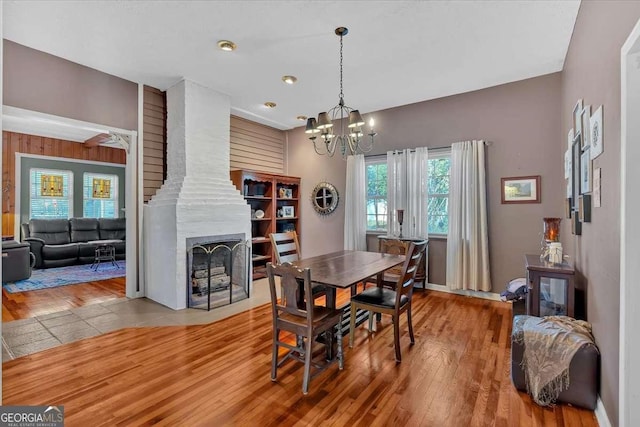 dining room featuring a notable chandelier, a fireplace, and wood finished floors